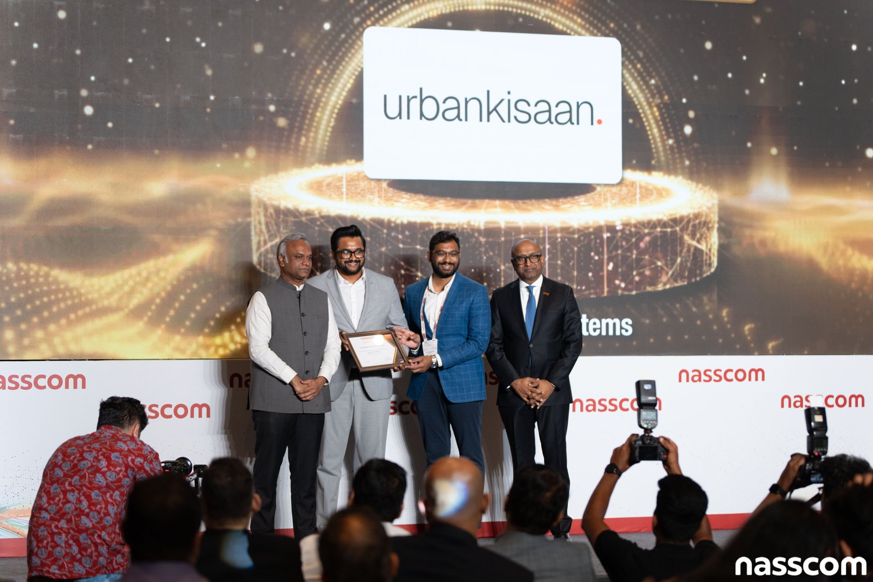 The UrbanKisaan award presentation on the Nasscom Emerge 50 stage, with the UrbanKisaan wordmark on the screen behind